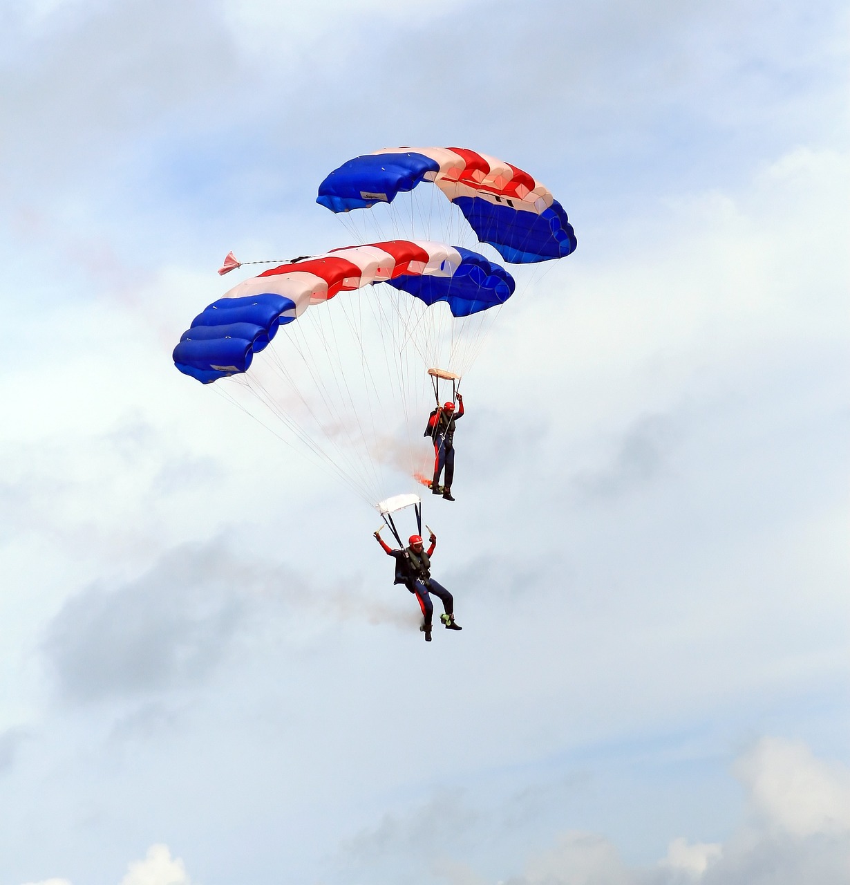 Skydiving in Connecticut - Skydivers fly under a red, white, and blue canopy in the clear blue sky